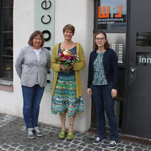 Drei Frauen stehen vor dem Eingang der Wirtschaftsförderung Lörrach, die mittlere hält einen Blumenstrauß