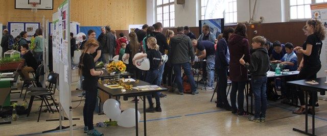 Blick in die volle Halle beim Tag der offenen Tür mit Stellwänden, Mitmachtischen und vielen Besuchern