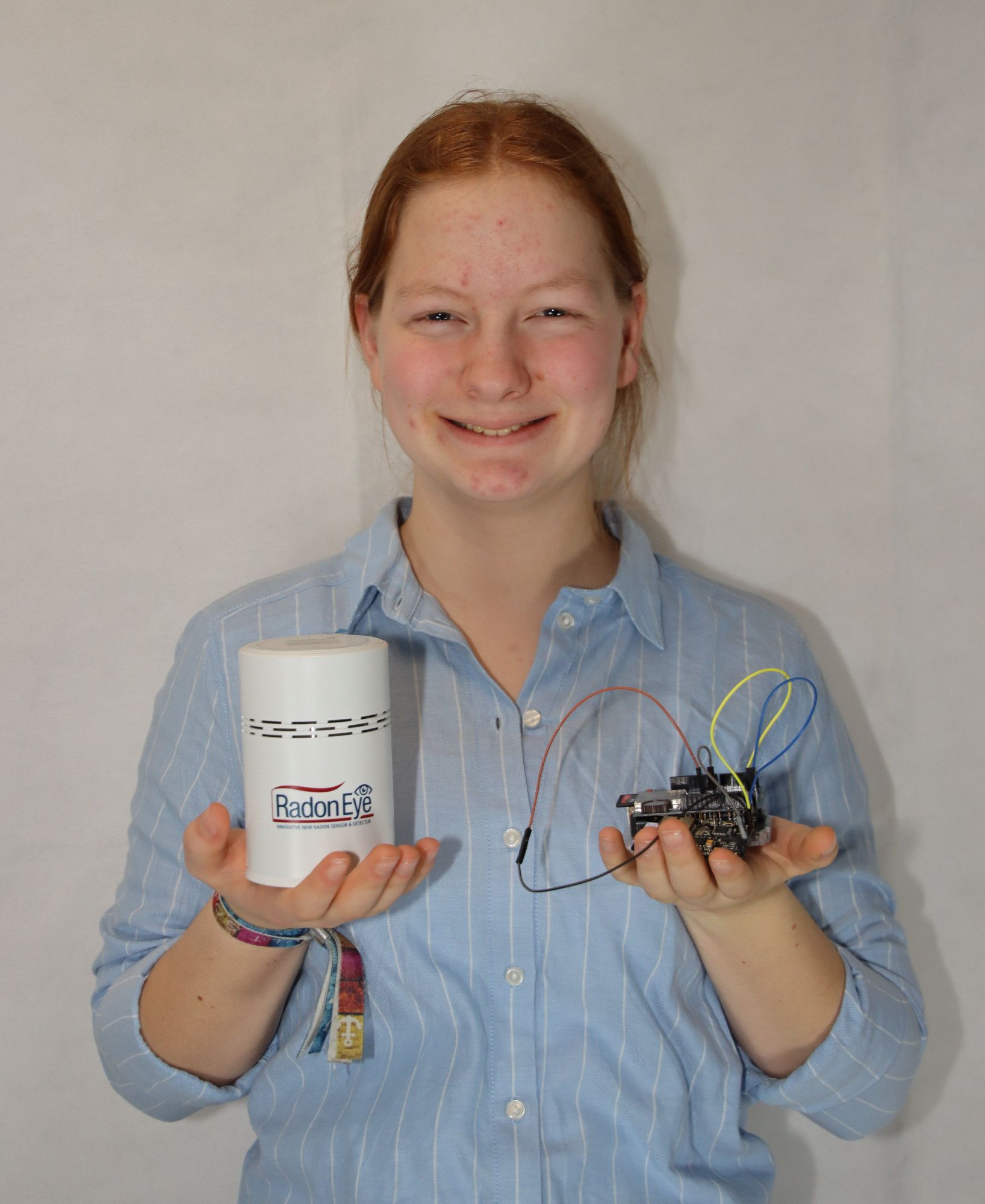 Eine Jungforscherin hält in einer Hand ein Radon-Messgerät und in der anderen ihre selbst gebaute Messelektronik