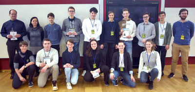 Gruppenfoto der Wettbewerbsteilnehmenden in zwei Reihen, einige halten Pokale und Urkunden