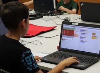 Ein Junge programmiert am Laptop ein Spiel aus bunten Scratch-Blöcken
